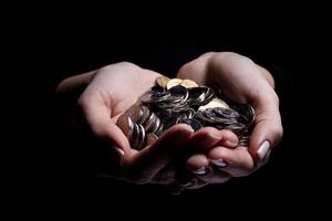 hands holding coins selective and soft focus isolated on black background with copy space. photo