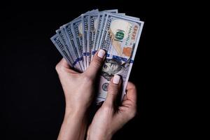 two hands with dollars. Closeup female hand giving money for something with isolated on black background,count, paying, shopping with dollar, corruption, counting dollar banknotes on black photo