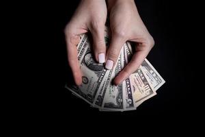 two hands with dollars. Closeup female hand giving money for something with isolated on black background,count, paying, shopping with dollar, corruption, counting dollar banknotes on black photo