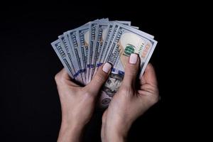 two hands with dollars. Closeup female hand giving money for something with isolated on black background,count, paying, shopping with dollar, corruption, counting dollar banknotes on black photo