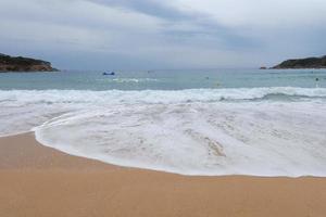 espuma de las olas cuando llegan a la arena de la playa foto