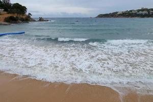 Foam from the waves as they reach the sand on the beach photo