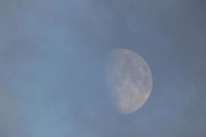 Near-full moon, seen through the clouds at sunset. photo