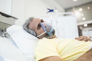 Portrait of an elderly patient, with oxygen mask, in a hospital bed. Man in bed with oxygen mask in hospital, Healthcare workers in the Coronavirus Covid19 pandemic photo