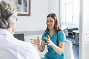 Patient with doctor in hospital waiting room discussing his symptoms. Young female doctor talking with her patient and explaining him his options and therapy photo