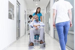 Wheelchair patient with professional female doctor and nurse specialist staff in corridor of hospital recovery center photo