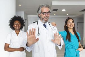 Closeup front view of group of mixed age doctors and nurses standing side by side and looking at the camera. Mature man doctor is in the front photo