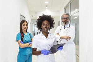 Closeup front view of group of mixed age doctors and nurses standing side by side and looking at the camera. African American female doctor is in the front. photo