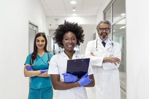 International doctor team. Hospital medical staff. Mixed race Black and Caucasian doctor and nurse meeting. Clinic personnel wearing scrubs and stethoscope. Coronavirus outbreak. photo