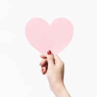 Close up women holding pink blank  paper with heart shape on white background. photo