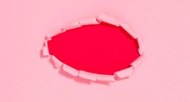 Top view of pink torn paper on red background. photo