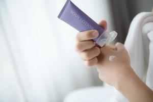 Close up of women applying body lotion cream on hand. photo