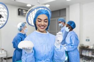 mujer cirujana plástica sosteniendo implantes mamarios de silicona en el interior de la sala de cirugía. concepto de cirugía estética foto