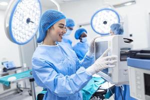 Diverse Team of Professional Surgeons Performing Invasive Surgery on a Patient in the Hospital Operating Room. Nurse Hands Out Instruments to surgeon, Anesthesiologist Monitors Vitals. photo