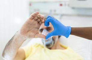 Doctor and patient make finger heart shape wearing blue disposable latex glove, rubber glove for professional medical safety and hygiene protection from Coronavirus disease COVID-19 and surgery photo