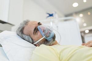 Portrait of an elderly patient, with oxygen mask, in a hospital bed. Man in bed with oxygen mask in hospital, Healthcare workers in the Coronavirus Covid19 pandemic photo