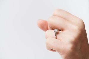 Cerca de un elegante anillo de diamantes de compromiso en el dedo de la mujer foto