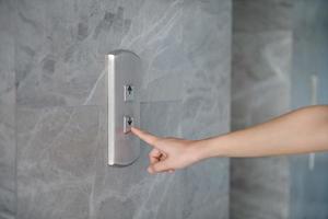 Cropped Hand Of Woman Pressing Push Button For Elevator On Wall photo