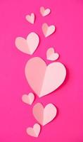 Shape of heart flying on pink paper background. photo