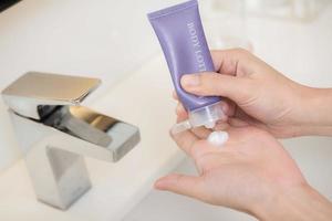 Close up of women applying body lotion cream on hand. photo