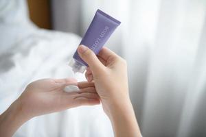 Close up of women applying body lotion cream on hand. photo