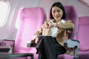 Attractive caucasian female passenger of airplane sitting in comfortable seat while working at modern laptop computer with mock up area using wireless connection on board photo