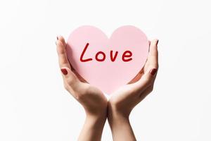 Close up women holding pink paper with heart shape on white background. photo