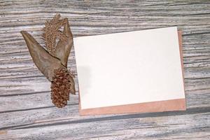 maqueta de tarjeta de felicitación de papel a5 con hojas secas sobre fondo de madera foto