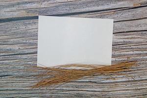 A5 paper greeting card mockup with dry leaves on wooden background photo