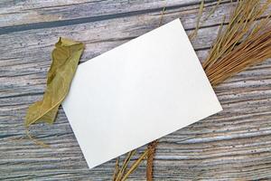 A5 paper greeting card mockup with dry leaves on wooden background photo