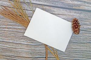 A5 paper greeting card mockup with dry leaves on wooden background photo