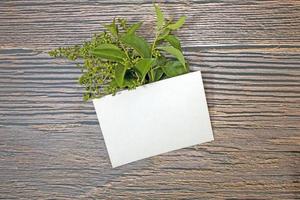 A5 paper greeting card mockup with green leaves on wooden background photo