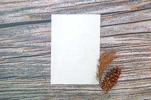 A5 paper greeting card mockup with dry leaves on wooden background photo