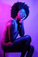 Positive black woman under neon light with eyes closed. photo