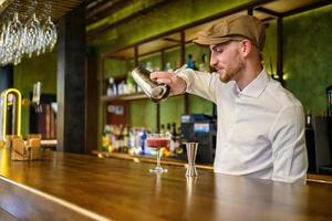 Bearded bartender preparing cocktail in pub photo