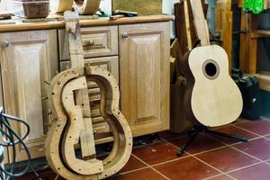 Wooden mould for making Spanish flamenco guitar, next to unfinished guitar, in luthier workshop. photo