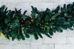 Christmas fir tree with lights on white brick background with copy space photo