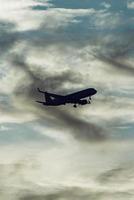 silueta de avión en el cielo al atardecer con nubes dramáticas foto