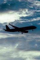 Silhouette of airplane in the sky at sunset with dramatic clouds photo