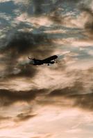 Silhouette of airplane in the sky at sunset with dramatic clouds photo