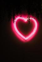 Neon red heart on black wall photo
