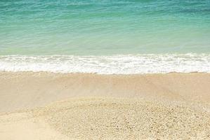 hermosa playa de arena y suave ola azul del océano foto