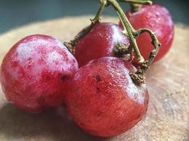 bodegón con uvas rosas maduras en un plato de madera
