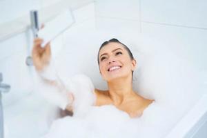 Young nice brunette woman having bath in bathtub photo