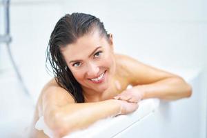 Young nice brunette woman having bath in bathtub photo