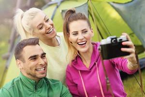 Group of friends camping in forest and taking selfie photo