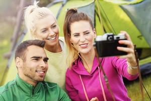 Group of friends camping in forest and taking selfie photo