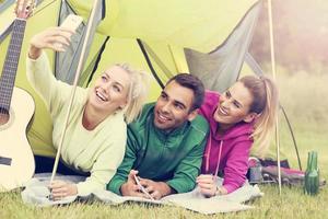 Group of friends camping in forest and taking selfie photo