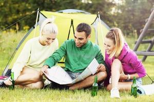 Group of friends camping in forest and looking at map photo