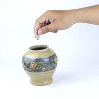 hand putting coins into a ceramic vase. Money management planning and financial concept photo